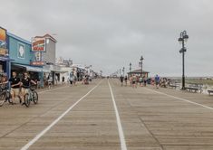 people are walking and riding bikes on the boardwalk