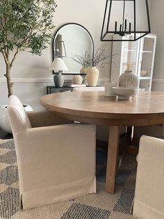 a dining room table with two chairs and a potted tree in the center area