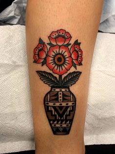 a tattoo on the leg of a woman with flowers in a vase