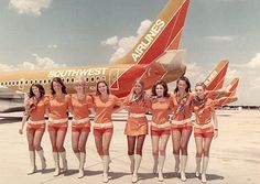 a group of young women standing next to each other on top of an airport tarmac