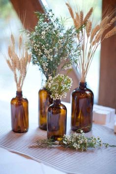 three brown glass bottles with flowers in them