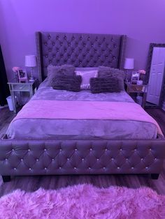 a large bed sitting in the middle of a room with purple carpet and pillows on top of it