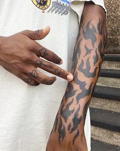 a man with tattoos on his arm pointing at something