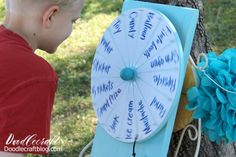 a young boy standing next to a tree with a paper fan on top of it