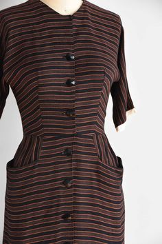 "Vintage 1950s cotton fitted dress. Vertical black and orange stripes. High collar, longer capped sleeves, seamed bust and nipped waist. Straight skirt with front pockets. Stream of front buttons for closure. State of garment | excellent Measurements ✂--- best fit | small bust | 35\" shoulders | not specified shoulder to waist | 15.5\" sleeves | not specified waist | 25-26\" hips | up to 39\" total length (shoulder to hem) | 39 \" ★★Visit The Shop★★ http://www.etsy.com/shop/seaofvintage ➸ Find t Short Sleeve Dresses With Vertical Stripes For Work, Retro Striped Lined Dress, Classic Striped Cotton Dress, Classic Striped Dresses For Daywear, Fitted Short Sleeve Dress With Striped Collar, Fitted Short Sleeve Dress With Vertical Stripes, Fitted Dress With Vertical Stripes And Short Sleeves, Vintage Short Sleeve Striped Dress, Retro Striped Dresses With Buttons