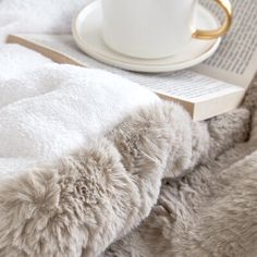 a white cup sitting on top of a table next to a book and coffee mug