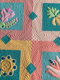 a close up of a quilt with flowers and leaves on the center, in pastel colors