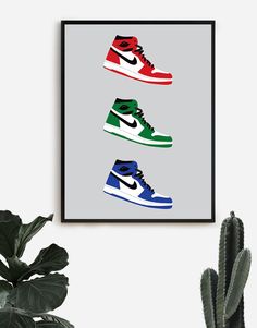 three pairs of sneakers are hanging on the wall next to a potted cacti