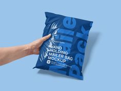 a hand holding a blue bag mockup on a light blue background with the package in it's left hand