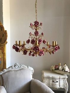 a chandelier hanging from the ceiling in a room with white furniture and pink flowers