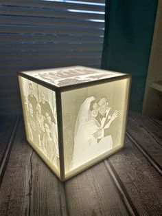 a light up box with an image of a bride and groom on the inside is sitting on a wooden table