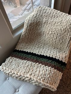 a crocheted blanket sitting on top of a white couch next to a window