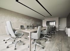 an empty conference room with grey chairs and white tables in front of a chalkboard wall