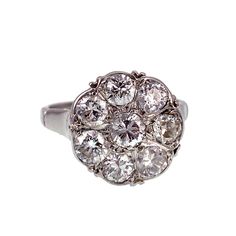 "Although diamond engagement rings among the aristocracy were common from the 15th century and on, it wasn't a widespread practice until the Victorian Era. A popular design was the \"daisy\", a solitaire diamond surrounded by smaller diamonds to represent a flower. Daisies were associated with loyalty, purity and innocence, the very attributes sought after in a new bride. Today, this style of ring is not reserved for matrimonial wear only. Cocktail rings and rings intended for the middle or index fingers are often designed in the flower-like shape, and are appropriate to wear for any occasion. This ring, made of an impressive 1.30 total carats in diamonds, is set in platinum, giving it an icy cold feel, just as if a daisy was caught in a winter storm, freezing the beautiful blossom in plac Memento Mori Ring, Buckle Ring, Cluster Engagement Ring, Art Nouveau Jewelry, Solitaire Diamond, 15th Century, Cluster Ring, Round Brilliant Cut Diamond, Victorian Era