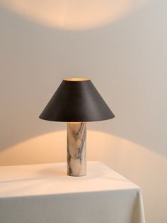 a table lamp sitting on top of a white table next to a black shade light