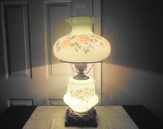 a lamp that is sitting on top of a table in front of a door with flowers painted on it