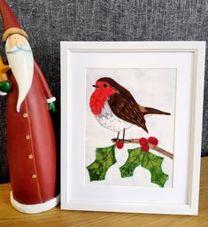 a red bird sitting on top of a wooden table next to a christmas decoration