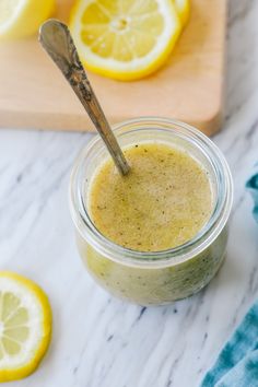 a glass jar filled with green smoothie next to sliced lemons