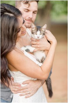 a man and woman holding a cat in their arms