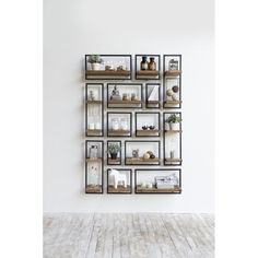 a white room with a shelf filled with pictures and other items on the wall next to a wooden floor