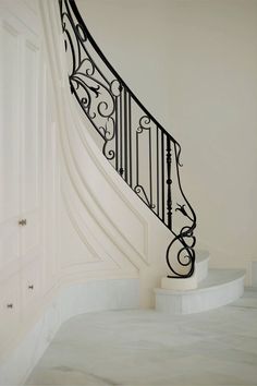 an elegant staircase with wrought iron railing and handrail in a white house or apartment