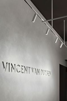 the entrance to an art gallery with large metal letters on the wall and ceiling lights above it