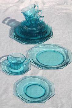 three blue glass dishes are sitting on a white tablecloth, and one is empty