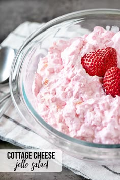 a bowl filled with cottage cheese and two strawberries on top of it next to a spoon