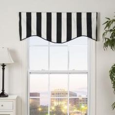 a window with black and white striped valance hanging over it's windowsill