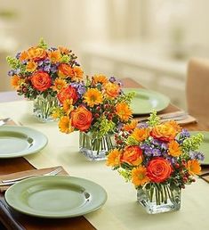 two vases filled with colorful flowers on top of a table next to plates and utensils