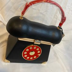 a black purse with a red and gold decoration on the front is sitting on a white sheet