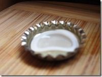 an empty bottle cap sitting on top of a wooden table next to a cupcake tin