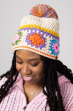 a woman wearing a multicolored crochet hat with pom - pom