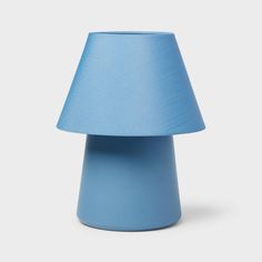 a blue table lamp on a white surface with a light blue shade over the top