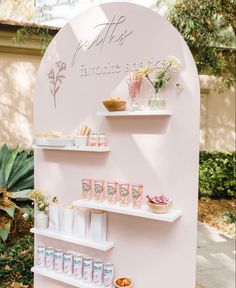 a pink wall with shelves filled with food and drinks on it's sides, along with other items