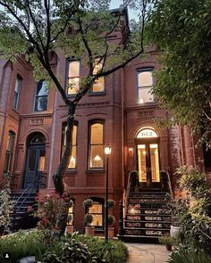 an old brick building with stairs leading up to the front door and trees on either side