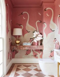 a bathroom decorated in pink and white with swans painted on the wall above the toilet