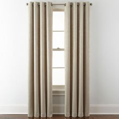 an open window with curtains in front of it and a white wall behind the curtain