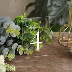 a table topped with green plants and a glass block that says happy 4 on it