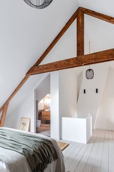 an attic bedroom with white walls and wood beams on the ceiling, along with a large bed