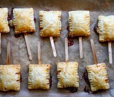 small pastries are lined up on a baking sheet with toothpicks in them