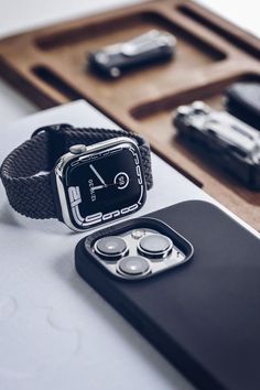 a cell phone and watch sitting next to each other on top of a white table