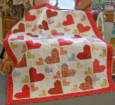 a quilted blanket with hearts on it in a room full of other fabrics and fabric