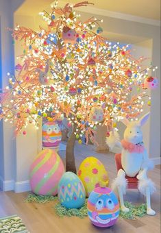 an easter tree is decorated with colorful eggs and other decorative items in front of it