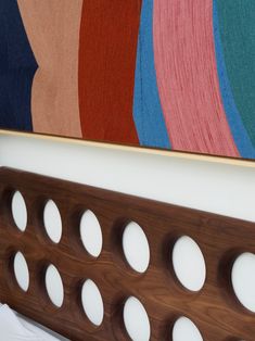 a close up of a wooden frame with circles on it in front of a painting