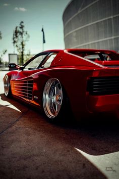 a red sports car parked in front of a building with the sun shining on it