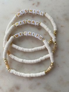 three white and gold beaded bracelets on a marble surface