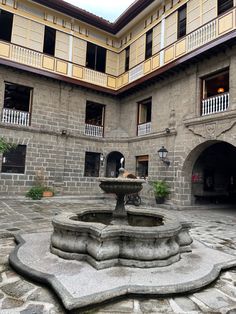 the courtyard of an old building with a fountain in the center and several balconies on the second floor