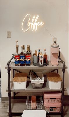 a coffee bar with various drinks and condiments on it's shelf next to a neon sign that says coffee