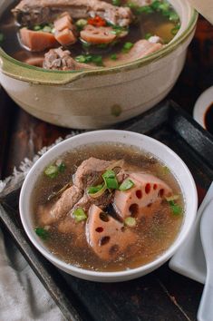 a bowl of soup with meat and vegetables in it on a tray next to another bowl